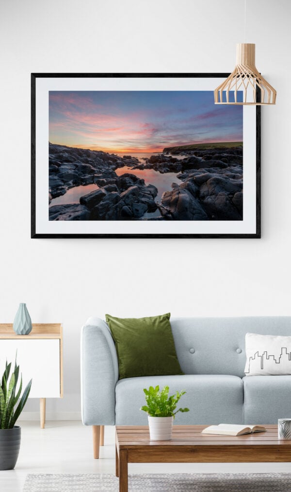 Sunrise view of the rocks and water of Loves Bay. Framed in black